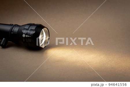 A bright beam of light from a flashlight shines on a brown recycled craft paper background. Old grunge vintage highly textured paper background 94641556