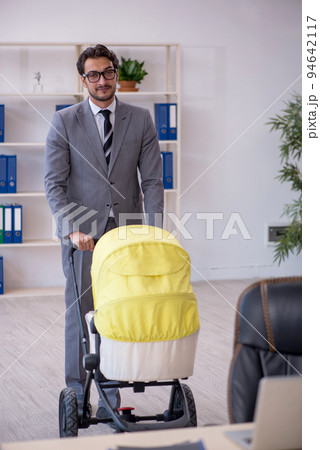 Young male employee looking after new born at workplace Young male employee looking after new born at workplace 94642117