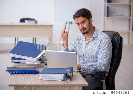 Young male employee and too much work in the office Young male employee and too much work in the office 94642261