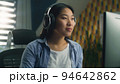 Asian woman in headset working on pc 94642862