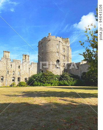 イギリス王室の公邸である石造りで円柱状の建物があるウィンザー城の外観と青空と芝生 イギリス王室の公邸である石造りで円柱状の建物があるウィンザー城の外観と青空と芝生 94643106