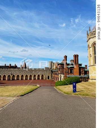 イギリス王室の公邸で石造りの建物があるウィンザー城と構内に建つ聖ジョージ礼拝堂の外観と青空と芝生 94643136