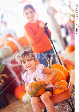 Two Young Girls Riding Wagon with Pumpkins. Two Young Girls Riding Wagon with Pumpkins. 94643218