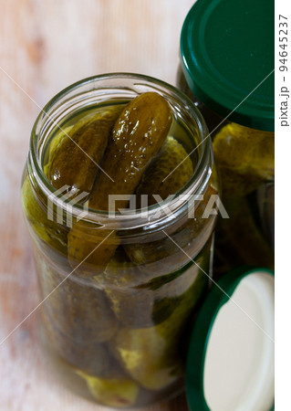 Glass jar with pickled cucumbers on a wooden table 94645237