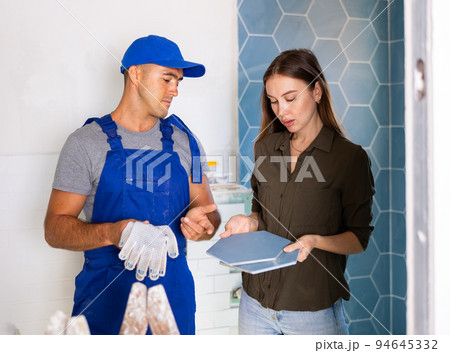 Tile setter discussing works in bathroom with woman Tile setter discussing works in bathroom with woman 94645332