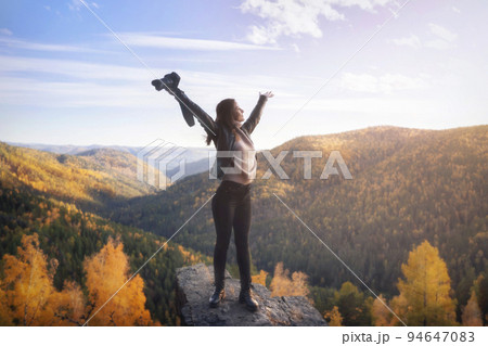 a female photographer at the top of the mountain spread her arms in joy of freedom and space. Landscape shooting of nature and travel concept in autumn a female photographer at the top of the mountain spread her arms in joy of freedom and space. Landscape shooting of nature and travel concept in autumn 94647083