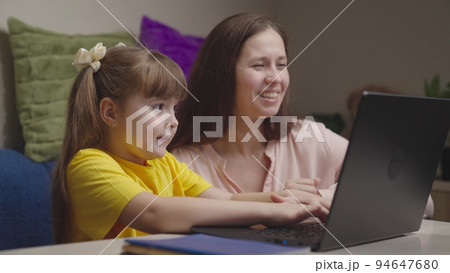 cheerful happy mom with child doing homework laptop. american education online. teamwork. happy family. child kid daughter hugs parent mother. together win going to success. maternal care love kid. cheerful happy mom with child doing homework laptop. american education online. teamwork. happy family. child kid daughter hugs parent mother. together win going to success. maternal care love kid. 94647680
