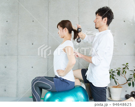 パーソナルトレーナーにダンベルトレーニングの指導を受ける日本人女性	 94648625