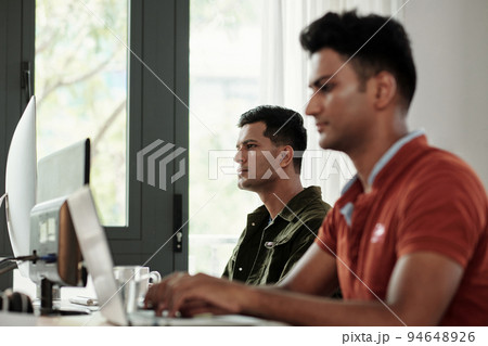 Concentrated software developers working on computers in modern office 94648926