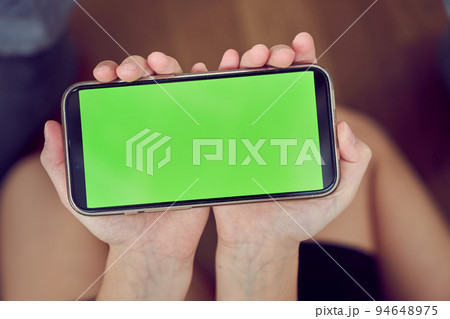 Close-up of children's hands using a phone with a green screen. A little girl is sitting on the floor and holding a smartphone with a colored key. High quality photo Close-up of children's hands using a phone with a green screen. A little girl is sitting on the floor and holding a smartphone with a colored key. High quality photo 94648975