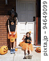 ハロウィンのコスチュームを着て装飾された家のドアの前にいる女の子2人 94649099