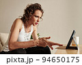 Emotional stylish mature woman watching shocking news on digital tablet 94650175