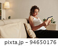 Smiling glam mature woman smiling when reading article on tablet computer 94650176
