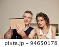 Glam rock mature couple making video call via application on tablet computer 94650178