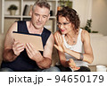 Happy stylish mature couple using tablet computer when video calling friends 94650179