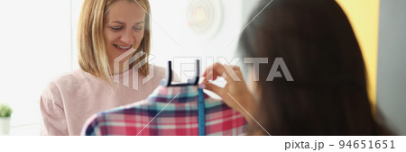 A woman seamstress shows a client a clothing 94651651