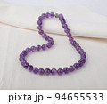 Purple stone necklace on white cloth background 94655533