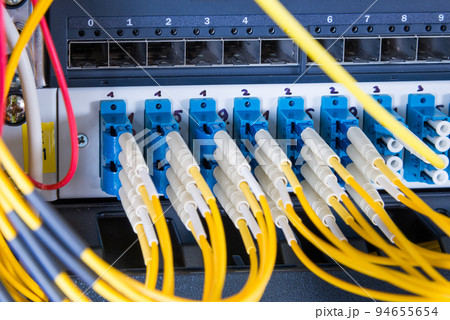 fiber optic cables plugged in network switch panel inside data center 94655654