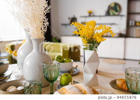 Bright spring mimosa in a ceramic geometric vase in the decor serving a festive or home table in the kitchen Bright spring mimosa in a ceramic geometric vase in the decor serving a festive or home table in the kitchen 94655876
