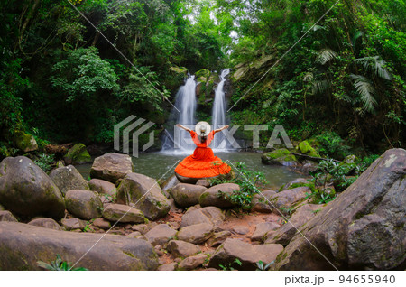 Beautiful woman in red dress in front of the Sapan Waterfall, Khun Nan National Park, Boklua District, Nan Province, Thailand. 94655940