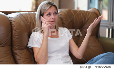 Young concentrated woman on sofa talking on mobile phone Young concentrated woman on sofa talking on mobile phone 94655980