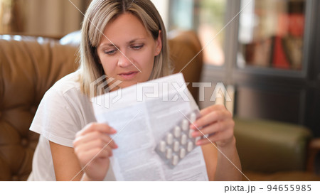 Young woman holds package of pills and reads medical instructions 94655985