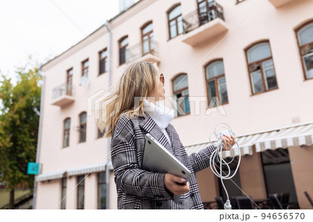 a business woman in the city on the street with a laptop in her hands is looking for a place where a business woman in the city on the street with a laptop in her hands is looking for a place where 94656570