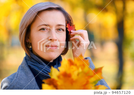 portrait of a beautiful woman with colorful yellow leaves, posing in a city park, bright sunny day in autumn portrait of a beautiful woman with colorful yellow leaves, posing in a city park, bright sunny day in autumn 94657120