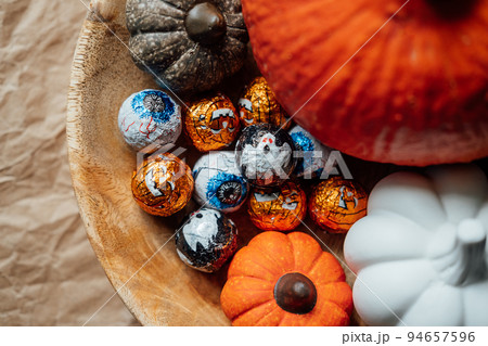 Sustainable and low waste Halloween candy for trick-or-treating. Foil covered eyeballs candies and Halloween decor in wooden plate 94657596