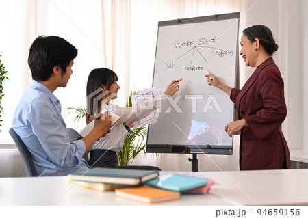 Experienced senior business leader giving a presentation, demonstrating business strategy on whiteboard at briefing Experienced senior business leader giving a presentation, demonstrating business strategy on whiteboard at briefing 94659156