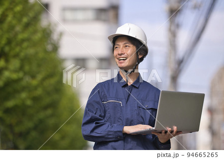 建設現場でパソコンを見る作業服の男性 94665265