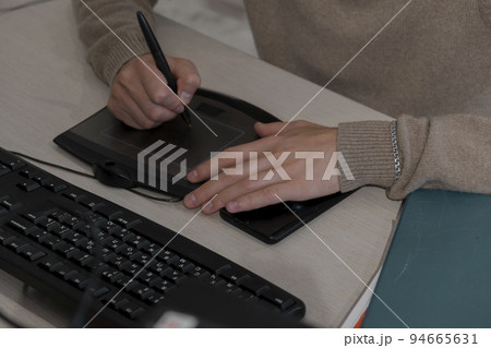 Close-up of the artist's hands of a designer drawing with a stylus on tablet 94665631