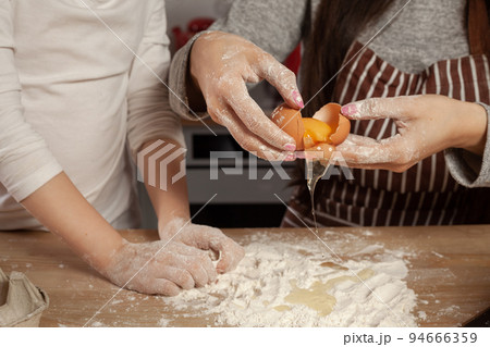 Mother and her daughter are baking a bread and having fun at the kitchen. 94666359