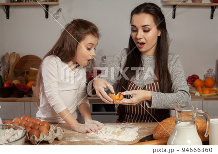 Mother and her daughter are baking a bread and having fun at the kitchen. 94666360