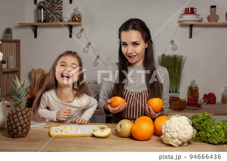 Mother and her daughter are doing a fruit cutting and having fun at the kitchen. 94666436