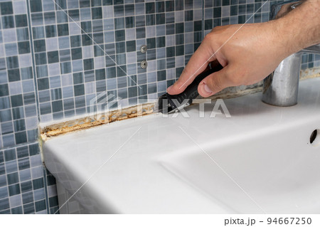 the master cleans the mold from the seams of the tiles in the bathroom the master cleans the mold from the seams of the tiles in the bathroom 94667250
