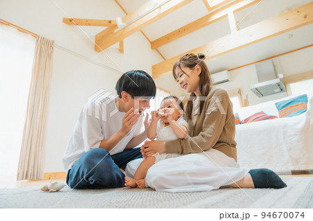 リビングで子供をあやす夫婦 94670074