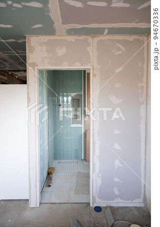 En suite bathroom renovation. Unfinished project of the new shower room, tiling, plastering, building niches and cupboards. view from the bedroom 94670336