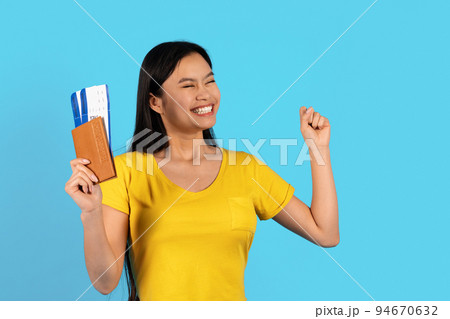 Satisfied excited young chinese female in yellow t-shirt with passport, air tickets looks at empty space Satisfied excited young chinese female in yellow t-shirt with passport, air tickets looks at empty space 94670632