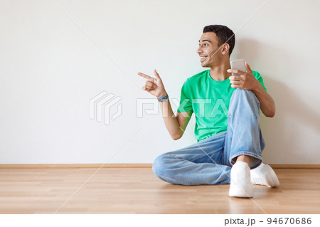 Special mobile offer. Excited man pointing aside at free space holding cellphone over light wall background Special mobile offer. Excited man pointing aside at free space holding cellphone over light wall background 94670686