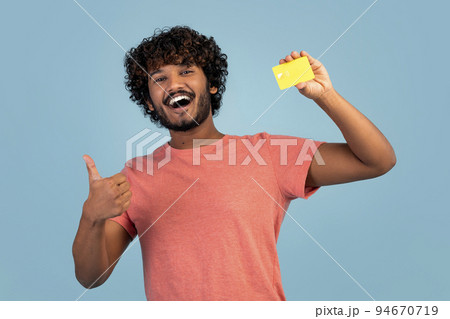 Happy eastern guy showing credit card and thumb up 94670719