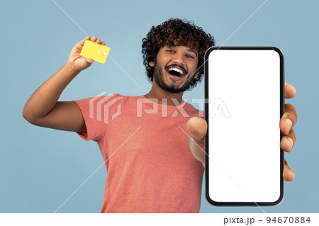 Happy indian guy showing cell phone and credit card, mockup Happy indian guy showing cell phone and credit card, mockup 94670884