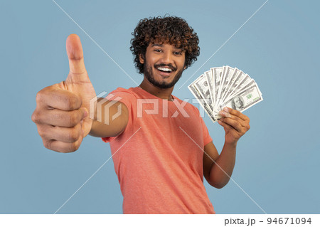 Cheerful indian man showing cash and thumb up Cheerful indian man showing cash and thumb up 94671094