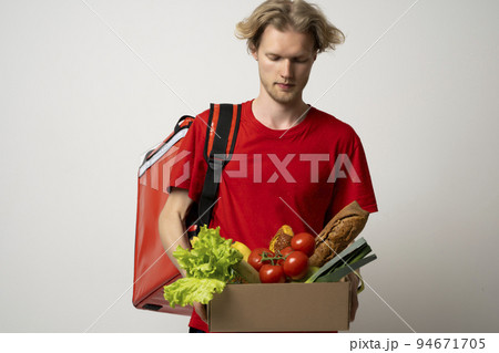 The guy delivers the basket full of groceries to the door of the house. Online shopping. Quality service of a restaurant. The guy delivers the basket full of groceries to the door of the house. Online shopping. Quality service of a restaurant. 94671705