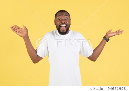 Cheerful African American Guy Shrugging Shoulders Over Yellow Studio Background 94671998