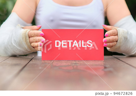 Details text on a red card held by female hands in casts 94672826