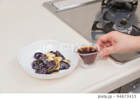 【茄子の揚げびたしを作る　炒めた茄子に麵つゆを入れる】 94673415