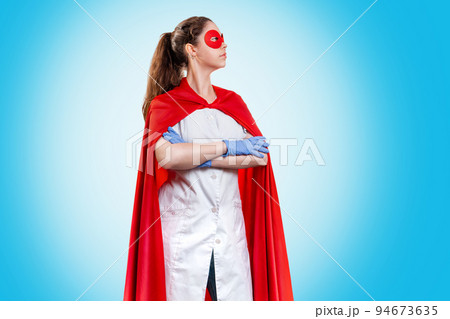 A doctor or nurse in medical gloves and a red superhero Cape on a blue background. Medical personnel during a coronavirus outbreak. Copy space. Super hero power for clinic and hospital 94673635