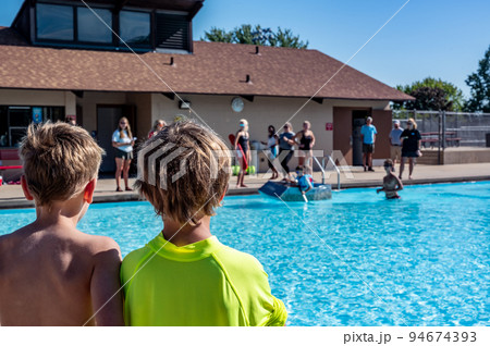 Two boys looking towards a cardboard boat floating in a pool. Two boys looking towards a cardboard boat floating in a pool. 94674393