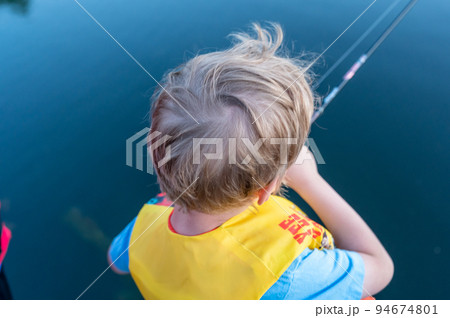 Boy on a fishing with blue water in background 94674801